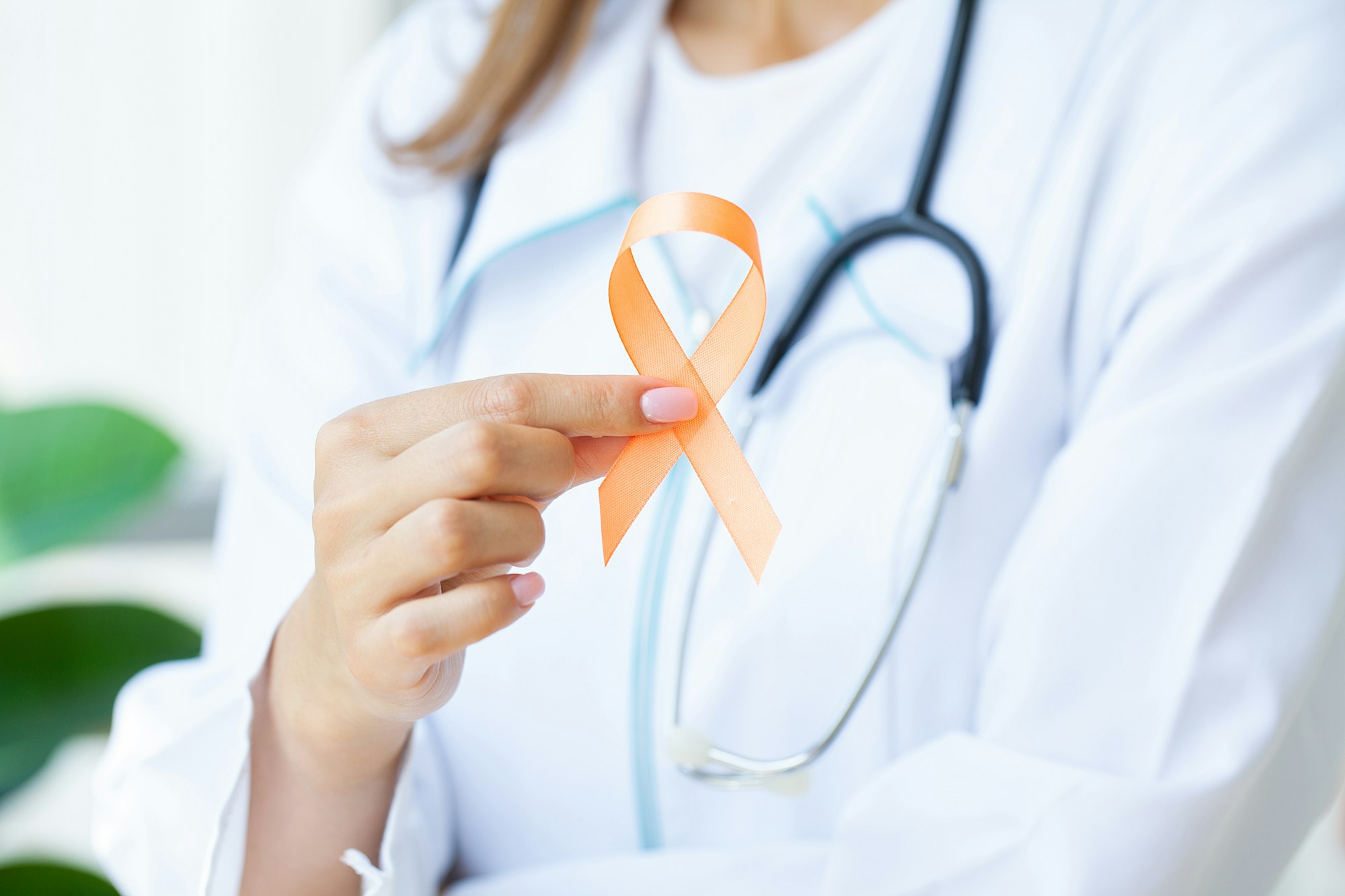 Close up of a doctor holding and showing orange awareness ribbon in her hands